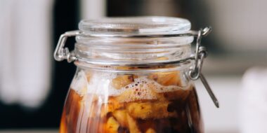 Glazen pot met gefermenteerde drank en drijvende ingrediënten