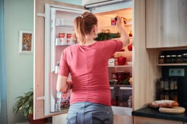 Vrouw kijkt in een open koelkast