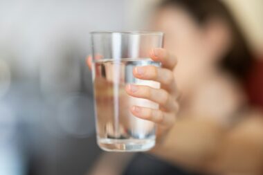 Glas water dat onder een keukenkraan wordt gevuld