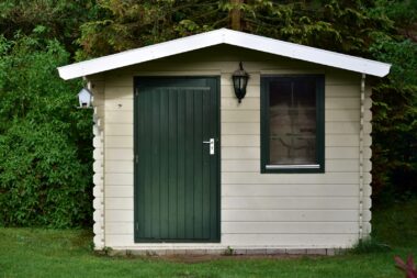 A small wooden shed with a green door and window