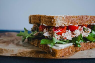 Broodje met romige kikkererwtensalade en bleekselderij op een snijplank