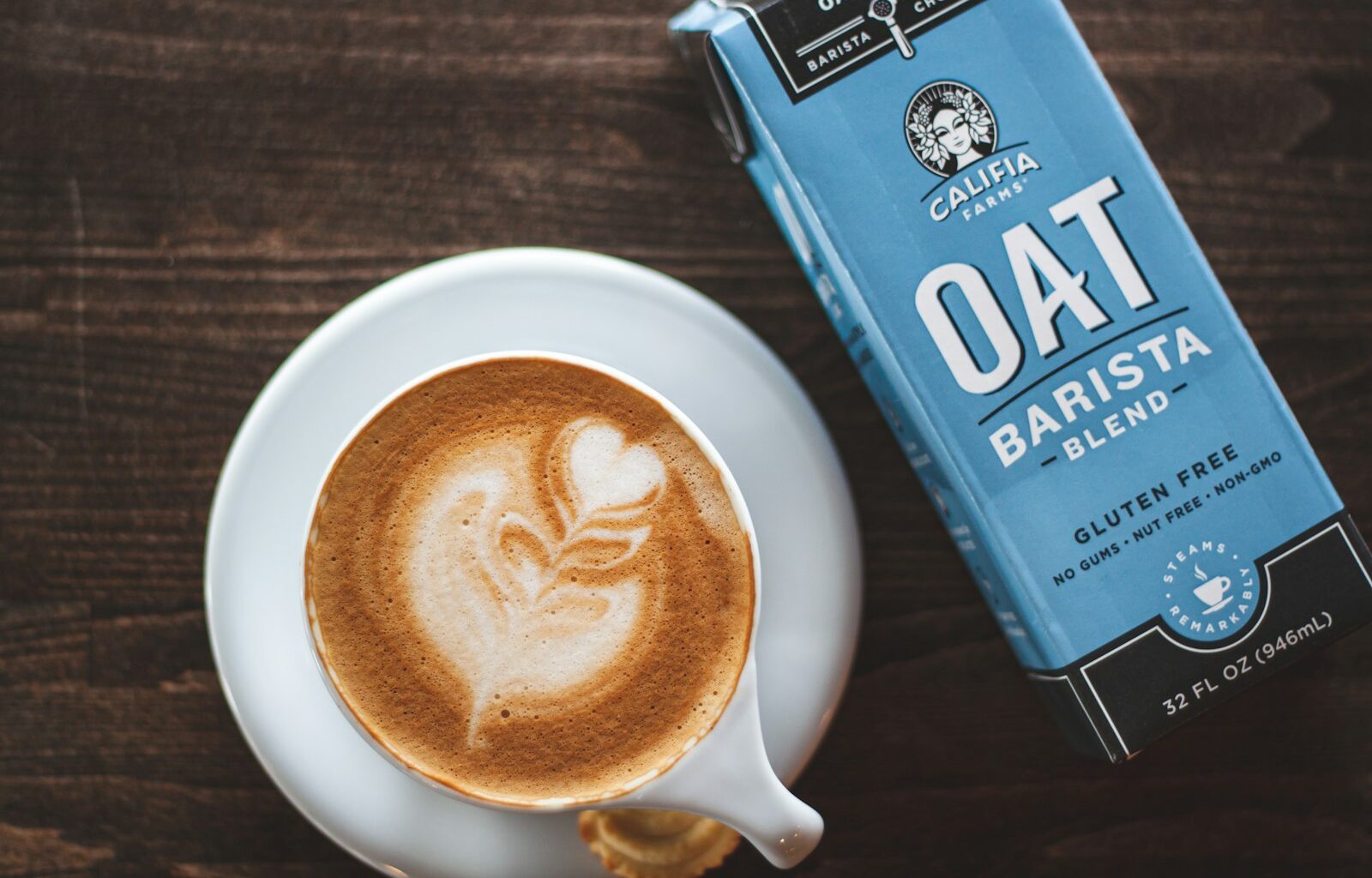 Latte met melkschuim en een pak havermelk op een toonbank