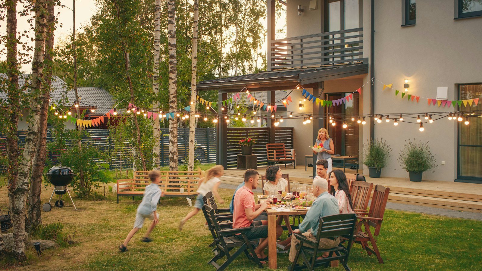 Gezelschap aan tafel tijdens een tuinfeest met lichtslingers