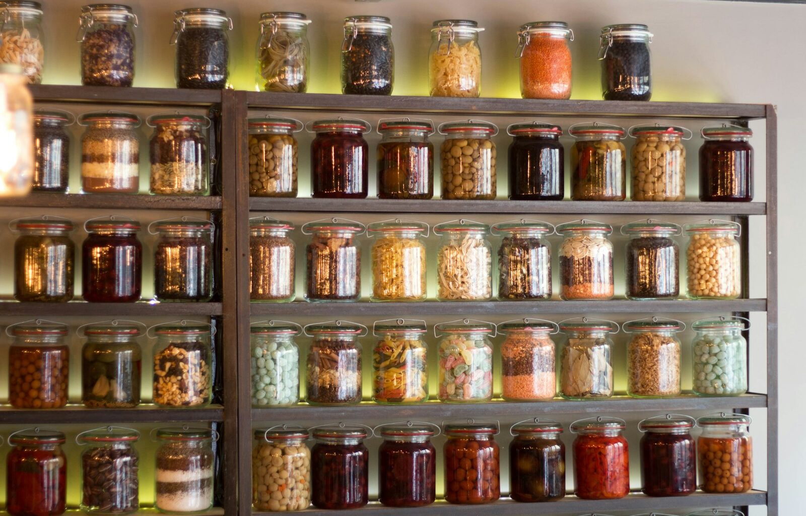 Open voorraadkast met potten peulvruchten, pasta en blikken tomaten