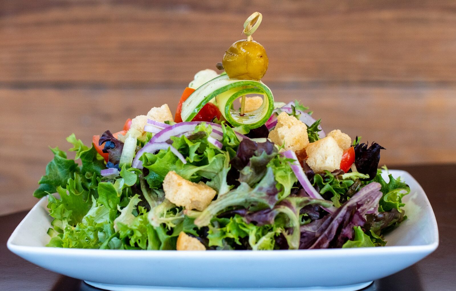 Salade in een kom met de dressing apart in een klein schaaltje ernaast
