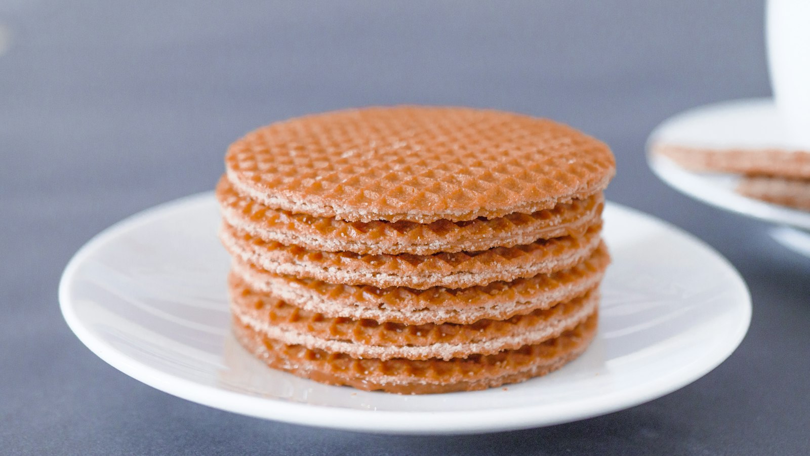 Stapel stroopwafels op een bordje naast een kop koffie