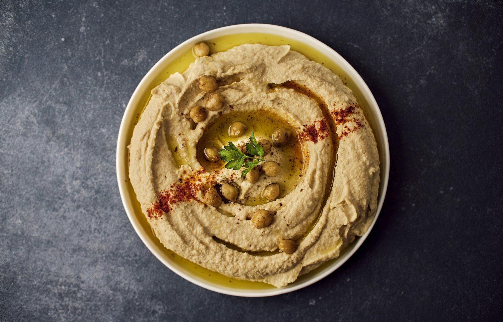 Kom hummus met olijfolie en kikkererwten op tafel